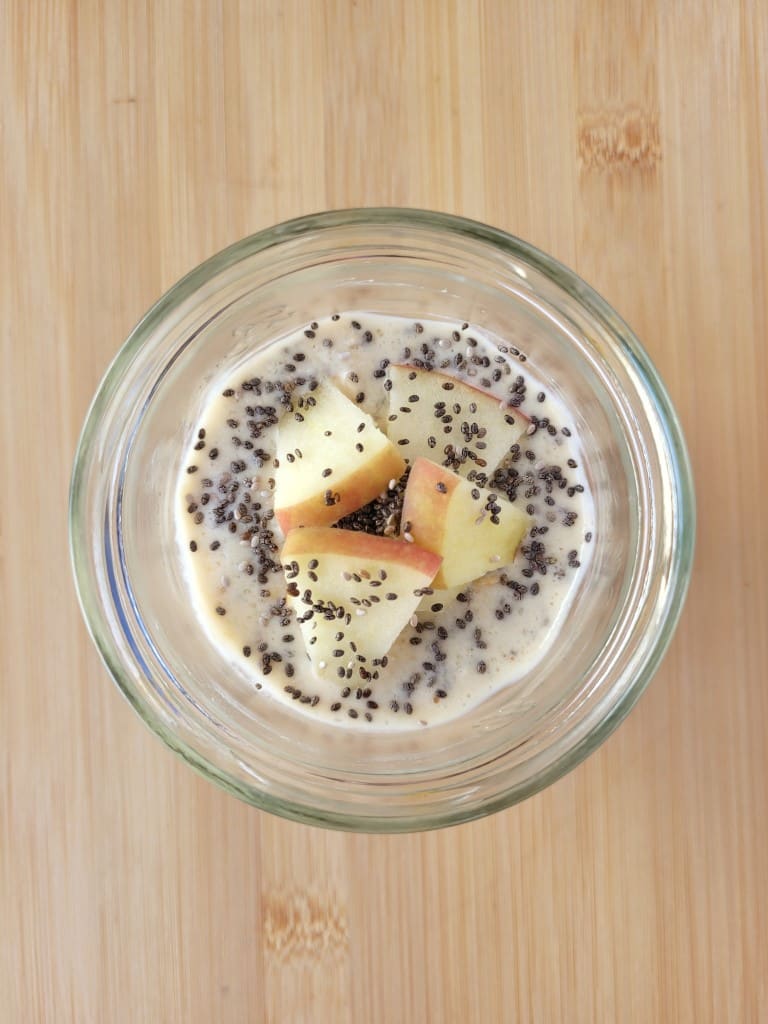 a jar of oats with a few apple pieces on the top as garnish